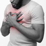 Cropped of afro man suffering from acid reflux or heartburn, symptomatic indigestion or gastritis disease, white background